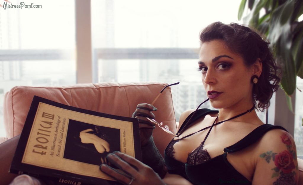 Dominatrix Mistress Pomf embodies BDSM roleplay fetish as she holds her sexy librarian glasses up to her lips and looks at you from afar while reading an erotica book from her BDSM fetish library.