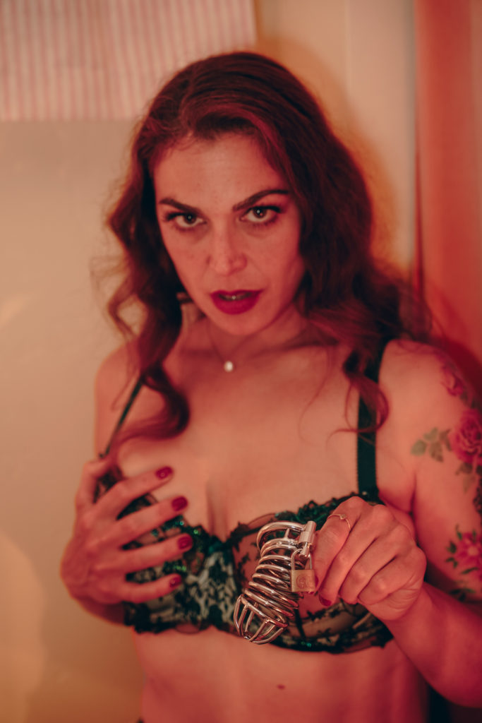 Colorado Dominatrix Mistress Pomf presenting a metal chastity cage and lock